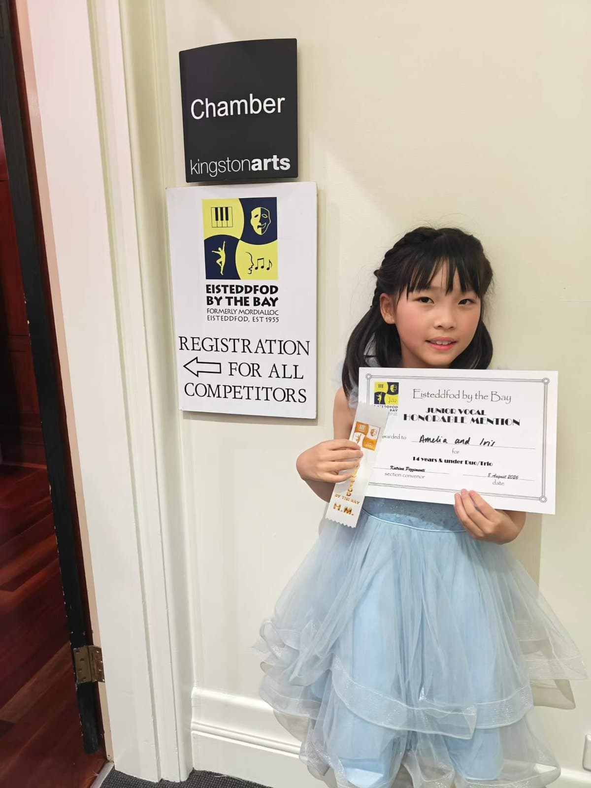 A student holding her certificate at the Kingston Arts chamber door during Eisteddfod by the Bay