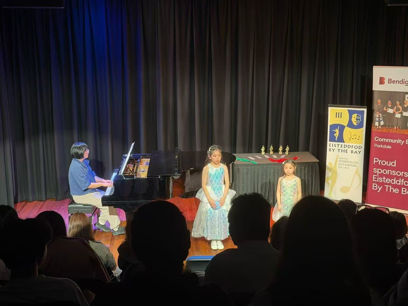 Students waiting to perform beside the piano at an eisteddfod session