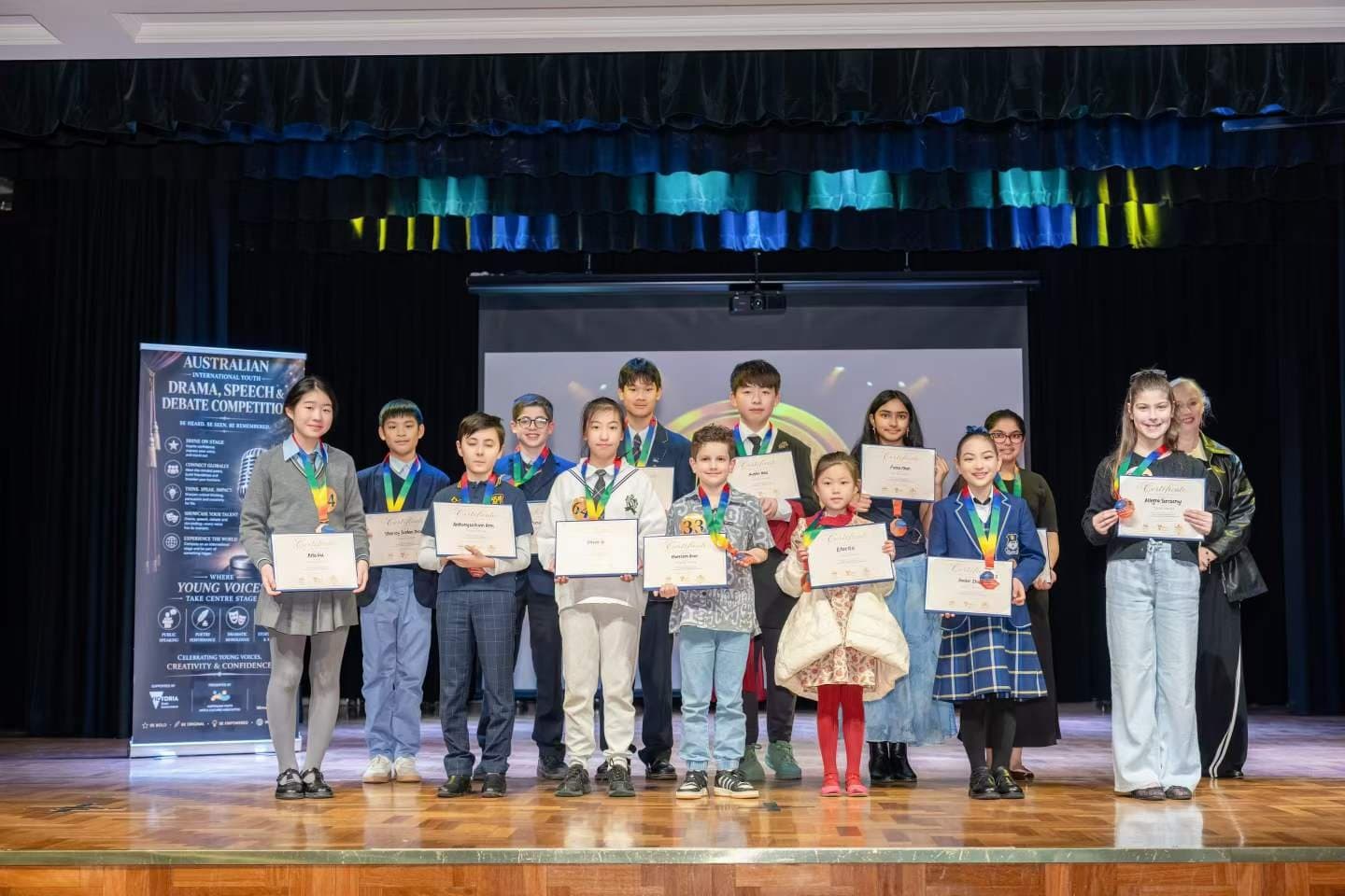 Speech and debate competitors lined up with certificates on a school hall stage