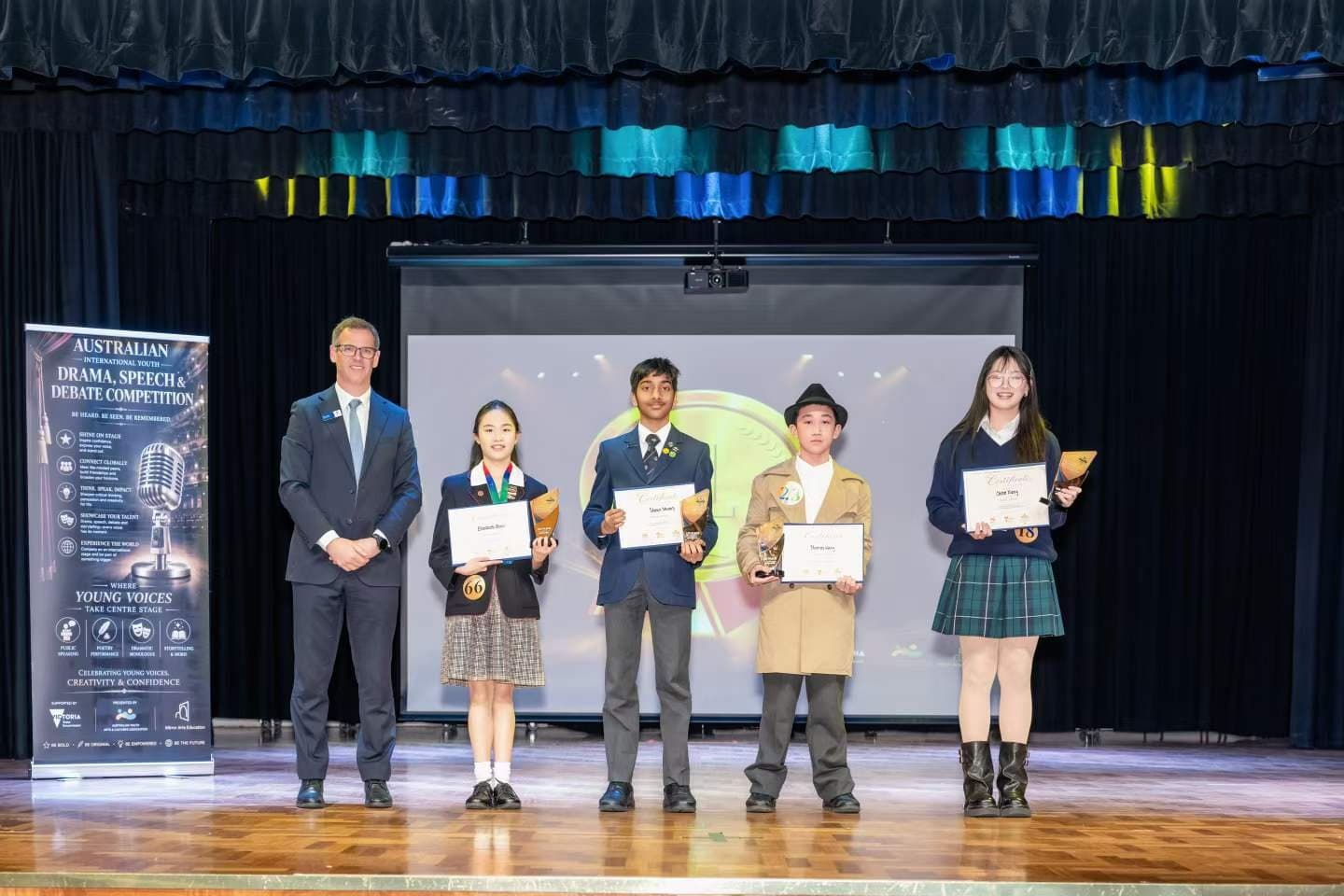 Students with certificates and trophies beside their adjudicator on stage