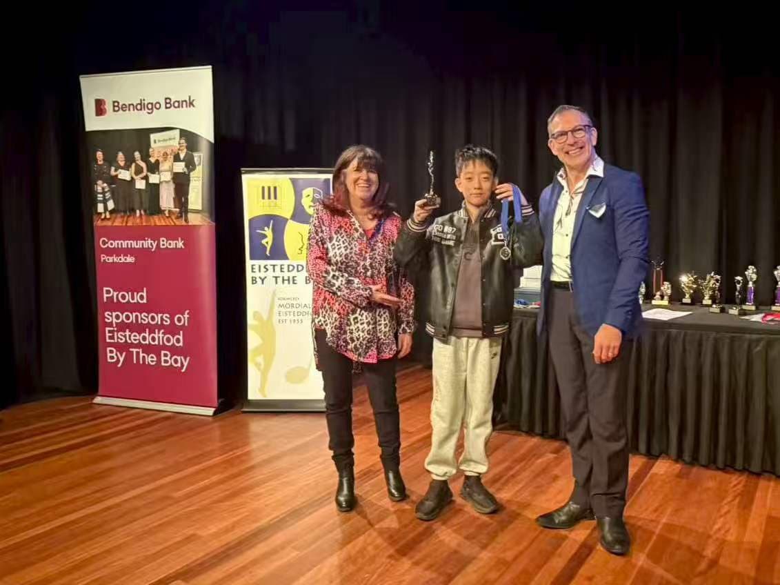 A student with his certificate between two adjudicators at Eisteddfod by the Bay