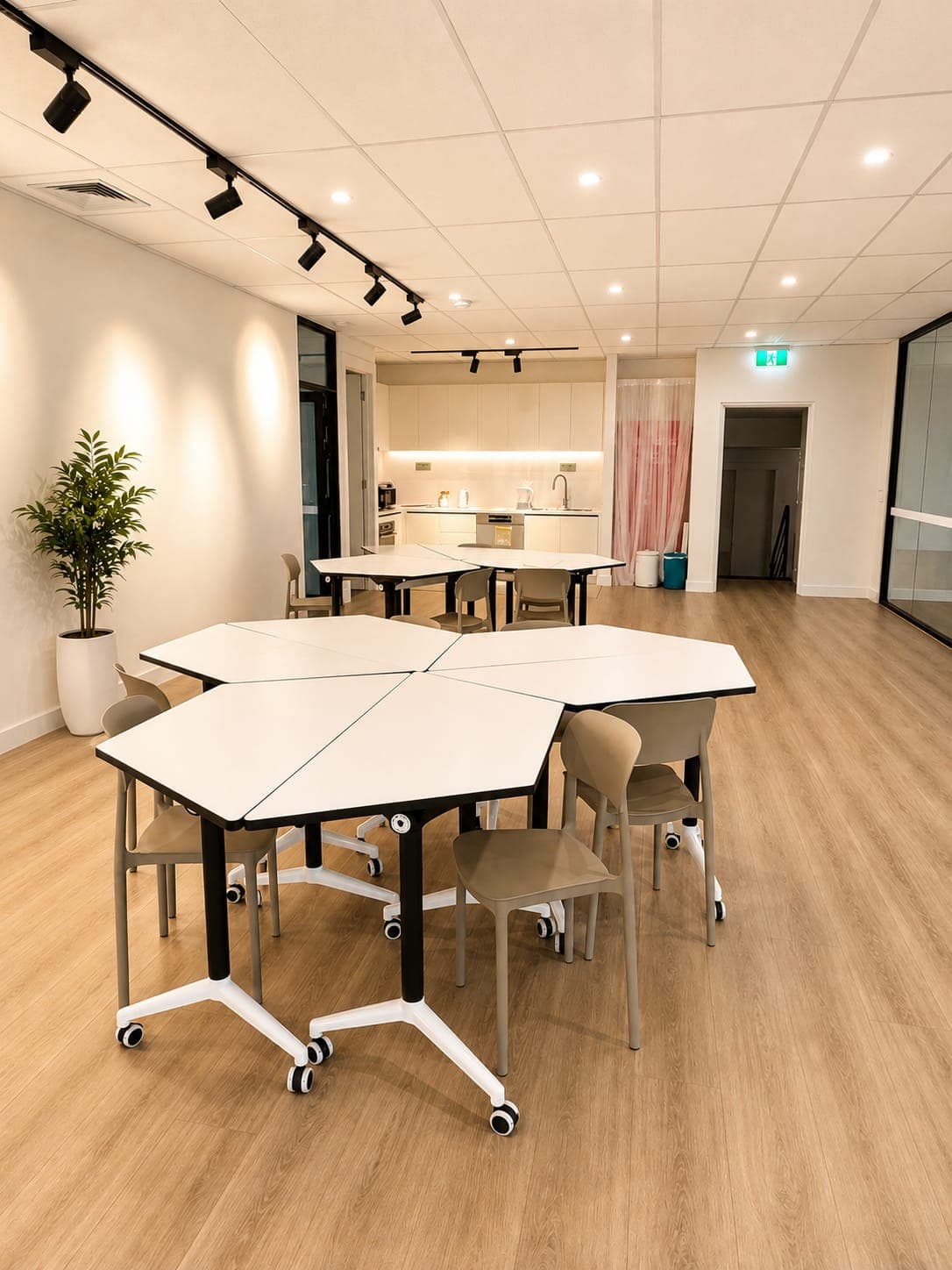 Hexagonal tables pushed together into a single work surface, with the kitchen and the parents' waiting area behind